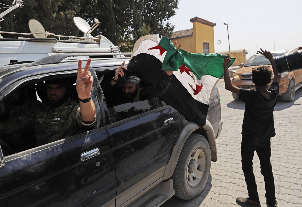 Members of Turkey-backed Syrian National Army (former FSA) flash the V-sign as they drive back ...