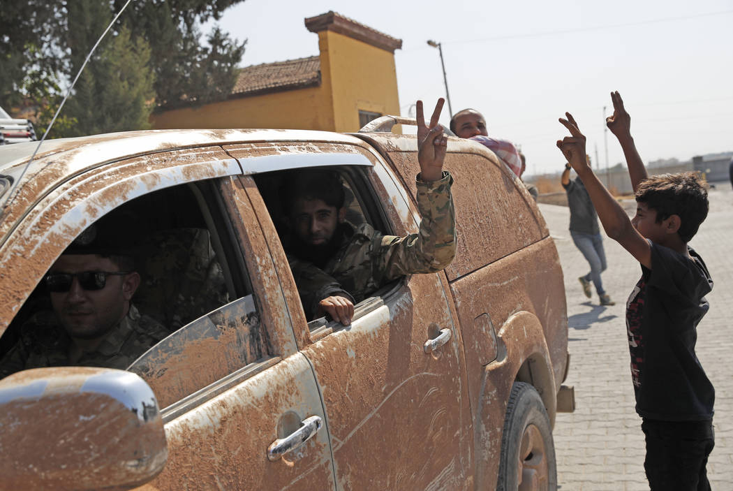 Members of Turkey-backed Syrian National Army (former FSA) flash the V-sign as they drive back ...