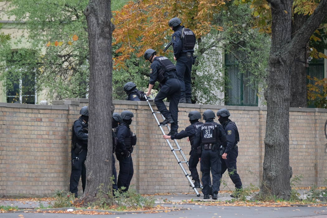 Police officers cross a wall at a crime scene in Halle, Germany, Wednesday, Oct. 9, 2019 after ...