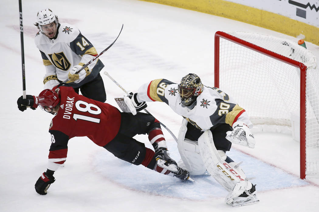 Arizona Coyotes left wing Christian Dvorak (18) gets clobbered by Vegas Golden Knights goaltend ...