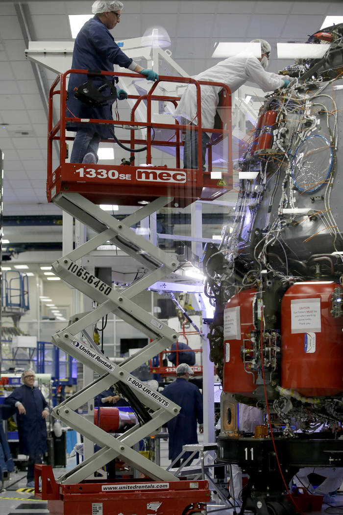 SpaceX employees work on the Crew Dragon spacecraft that will take astronauts to and from the I ...