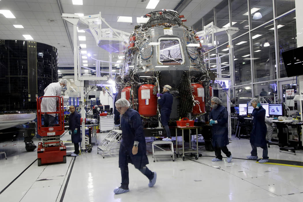 SpaceX employees work on the Crew Dragon spacecraft that will astronauts to and from the Intern ...