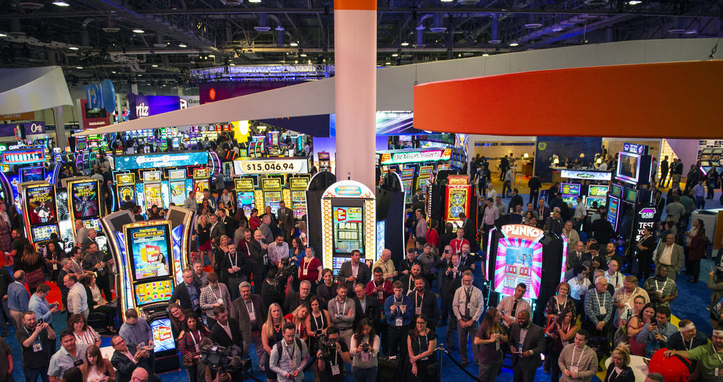 A crowd gathers at the IGT's booth as gameshow host Drew Carey leads the world debut of three I ...