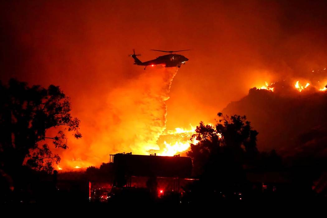 Water is dropped on a large brush fire Friday, Oct. 11, 2019, in Sylmar, Calif. (AP Photo/David ...