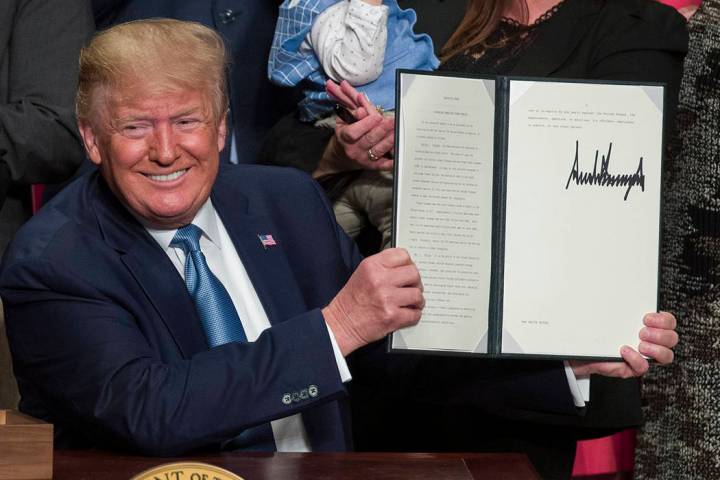 President Donald Trump holds up a signed executive order at the Ronald Reagan Building and Inte ...