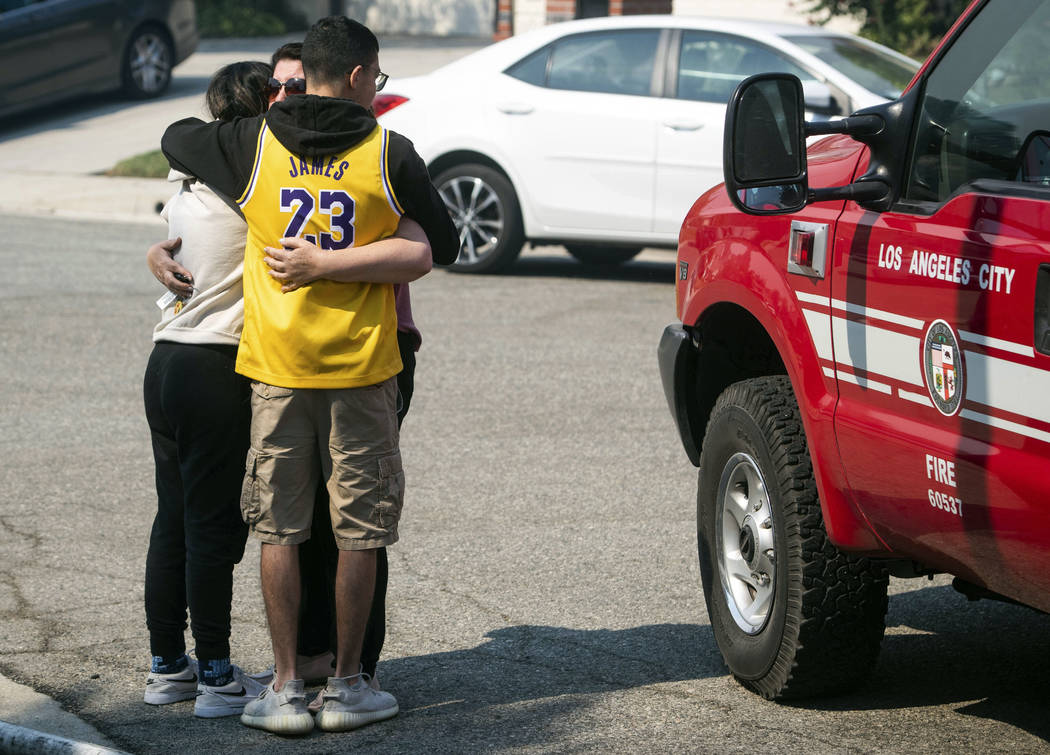 A family friend hugs The Manokian children, Serineh and Matthew after their family home on Hamp ...