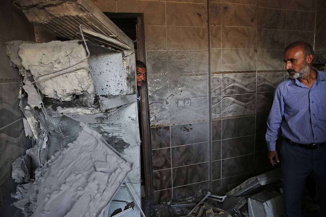 Halil Tokak, right, the neighborhood chief and another resident, inspect the damage on a house, ...