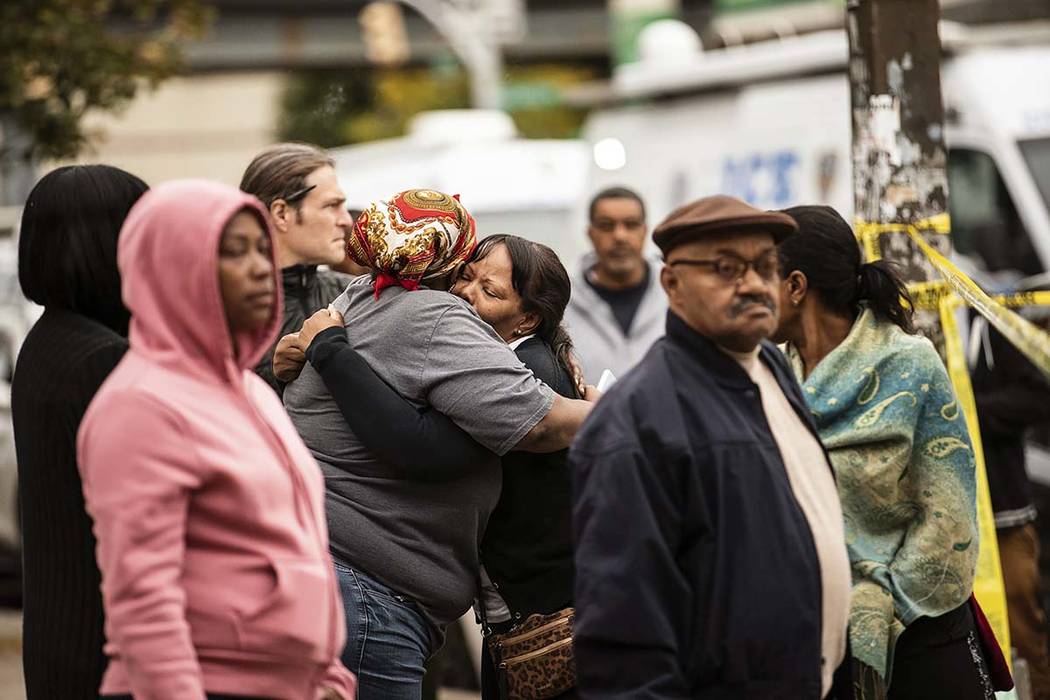 Two people embrace at the scene of a shooting in the Brooklyn borough of New York on Saturday, ...