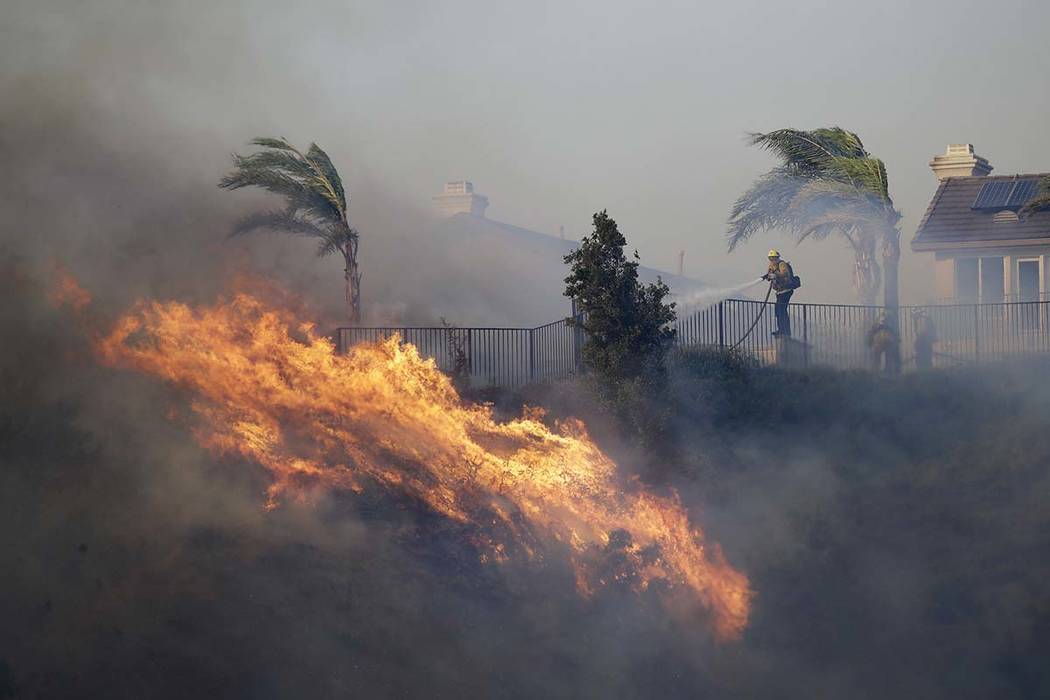 A firefighter sprays water in front of an advancing wildfire Friday, Oct. 11, 2019, in Porter R ...