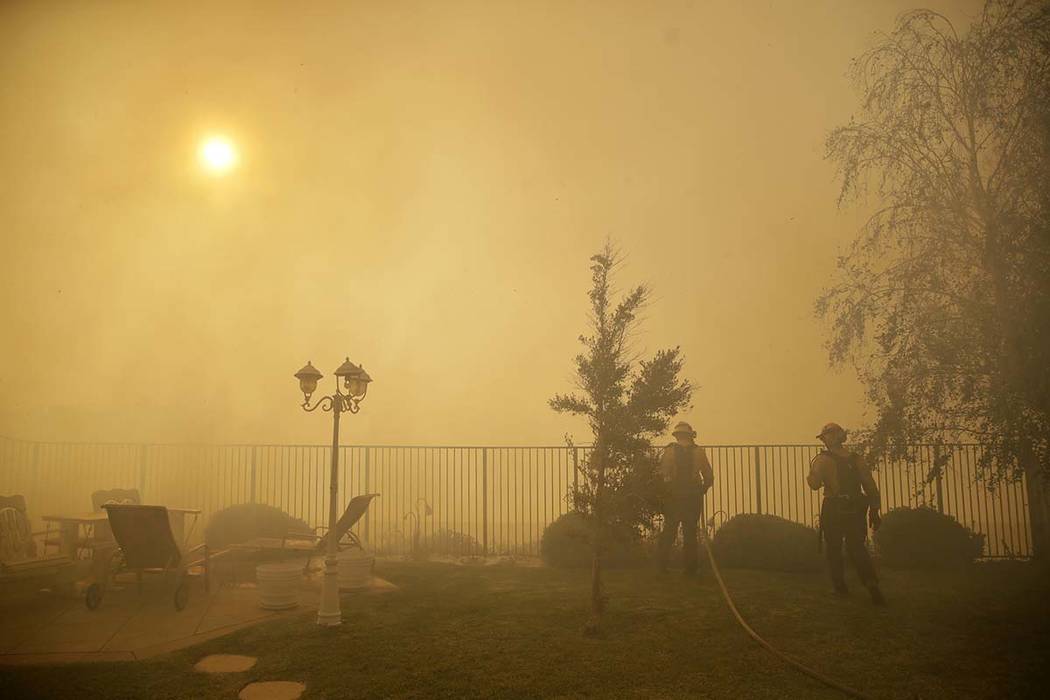 Firefighters make a stand on an advancing wildfire as smoke fills the air Friday, Oct. 11, 2019 ...