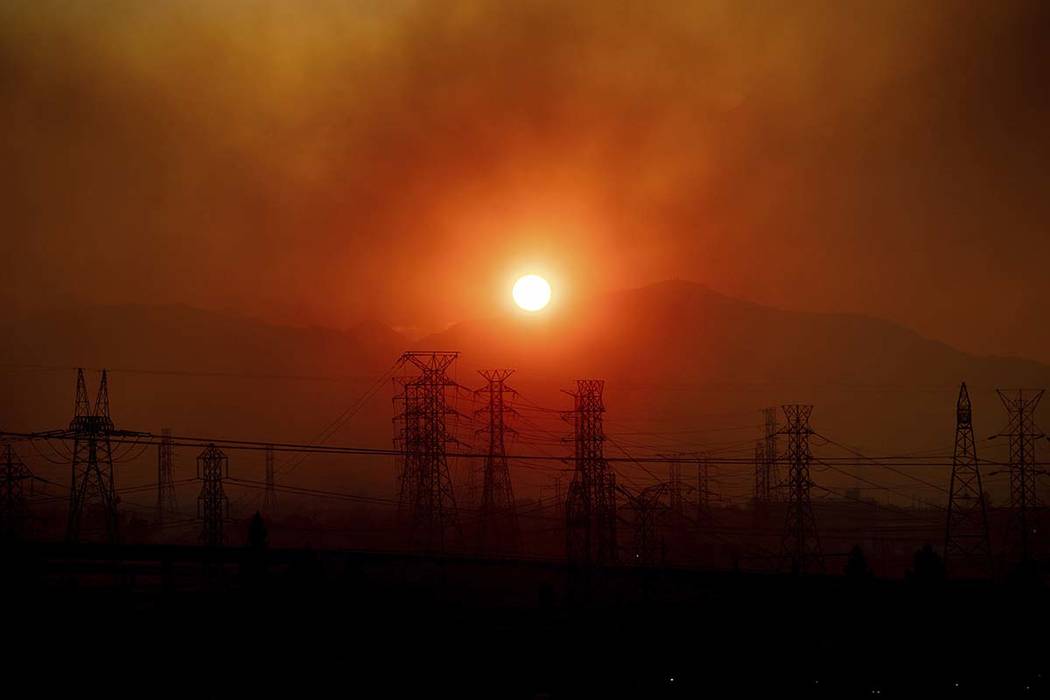 Smoke from the Saddleridge Fire hangs above power lines as the sun rises in Newhall, Calif., on ...