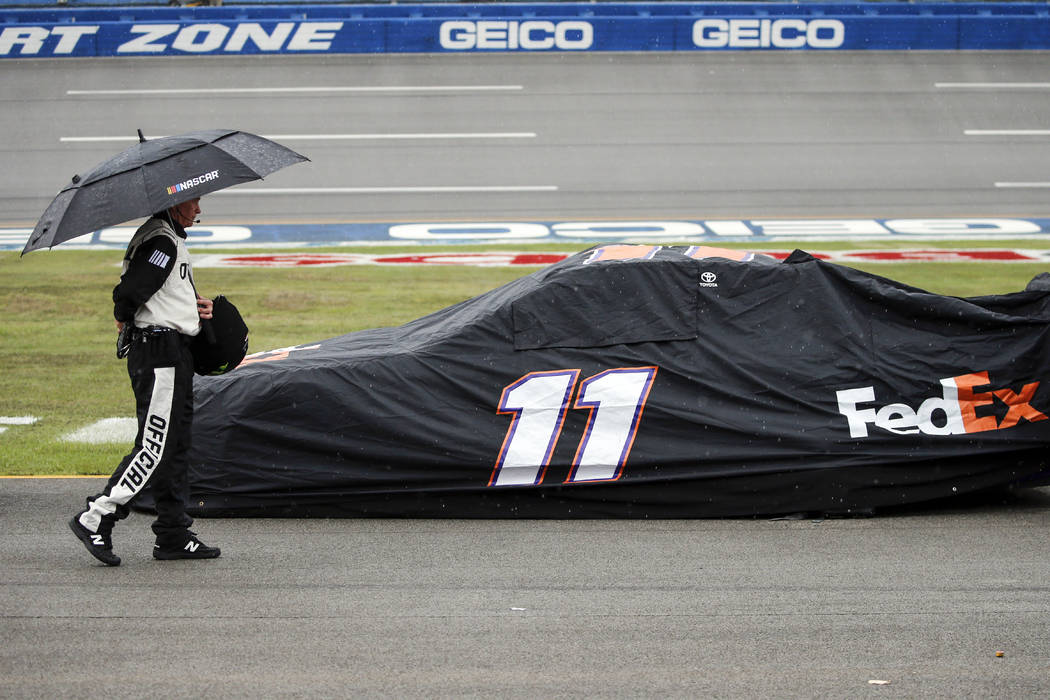 An official walks by the car of Denny Hamlin (11) car during a rain delay in a NASCAR Cup Serie ...