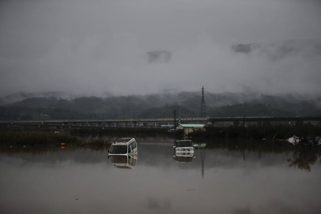 Two vehicles are submerged in floodwaters Monday, Oct. 14, 2019, in Hoyasu, Japan. Rescue crews ...