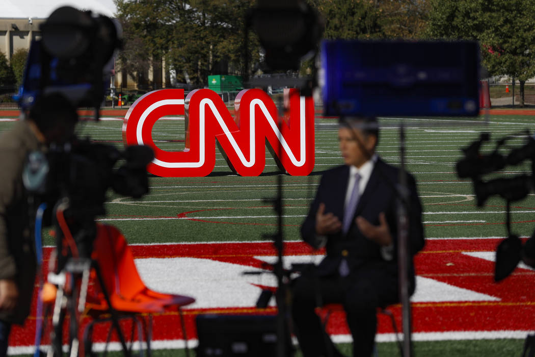 A journalist records video near a CNN sign on an athletic field outside the Clements Recreation ...