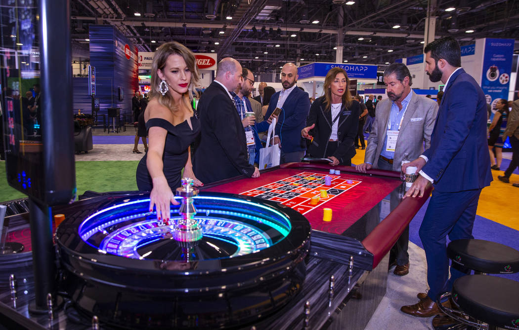 Attendees confer over a roulette table on display in the TCSJOHNHUXLEY exhibition space during ...