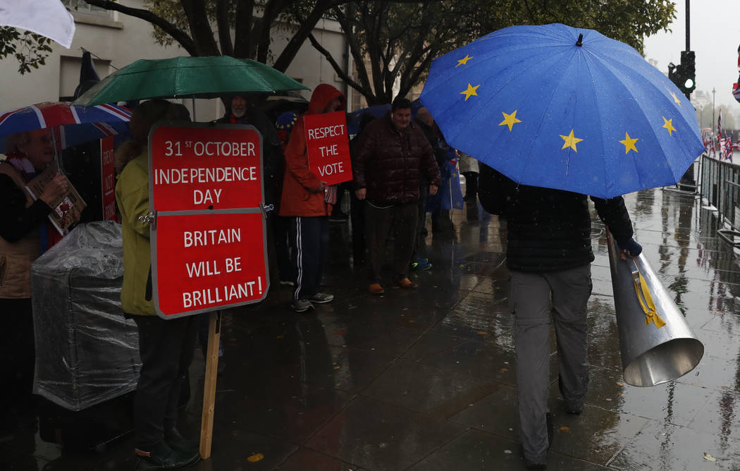 Anti-Brexiteer Steve Bray carries his megaphone past pro Brexit supporters as they shelter from ...