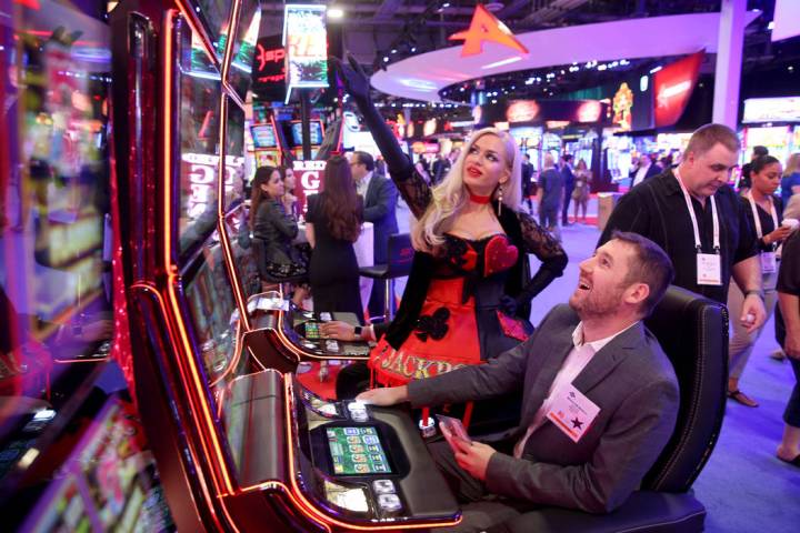 Joyce Jones of Las Vegas shows Maksym Maslii, of Digicode of Plano, Texas, how to play Jackpot ...