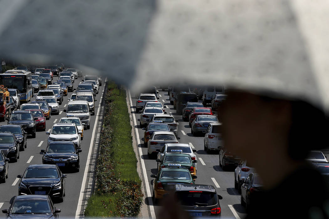 In an Aug. 13, 2019, file photo, a woman walks past vehicles on a city ring-road clogged with h ...