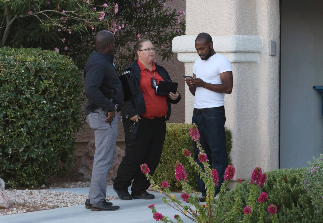 Investigators talk to a resident neat the scene where police investigate a shooting involving a ...