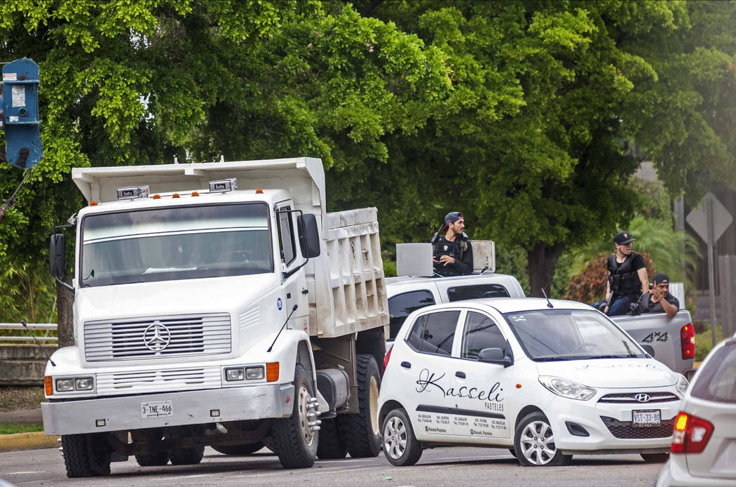 Unidentified gunmen block a street in Culiacan, Mexico, Thursday, Oct. 17, 2019. An intense gun ...