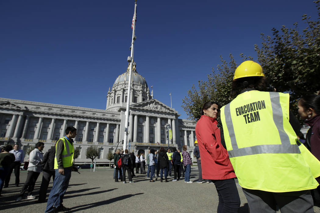 An evacuation team member stands with participants during an earthquake preparedness drill acro ...