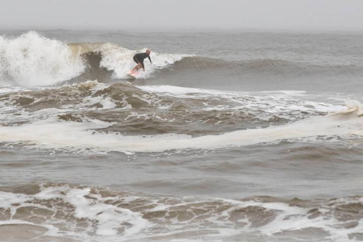 A surfer finds a wave in Mexico Beach, Fla. after Tropical Storm Nestor hit the town on Saturda ...