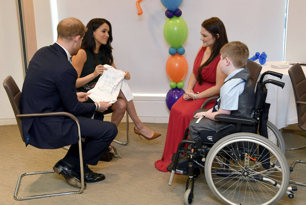 Britain's Prince Harry and Duchess of Sussex, left, look at a t-shirt designed by William Mgee ...