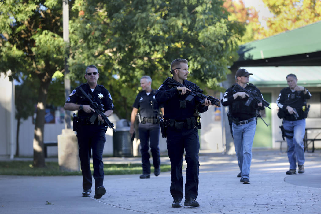 Santa Rosa police officers carry guns as they search the campus of Ridgway High School for susp ...