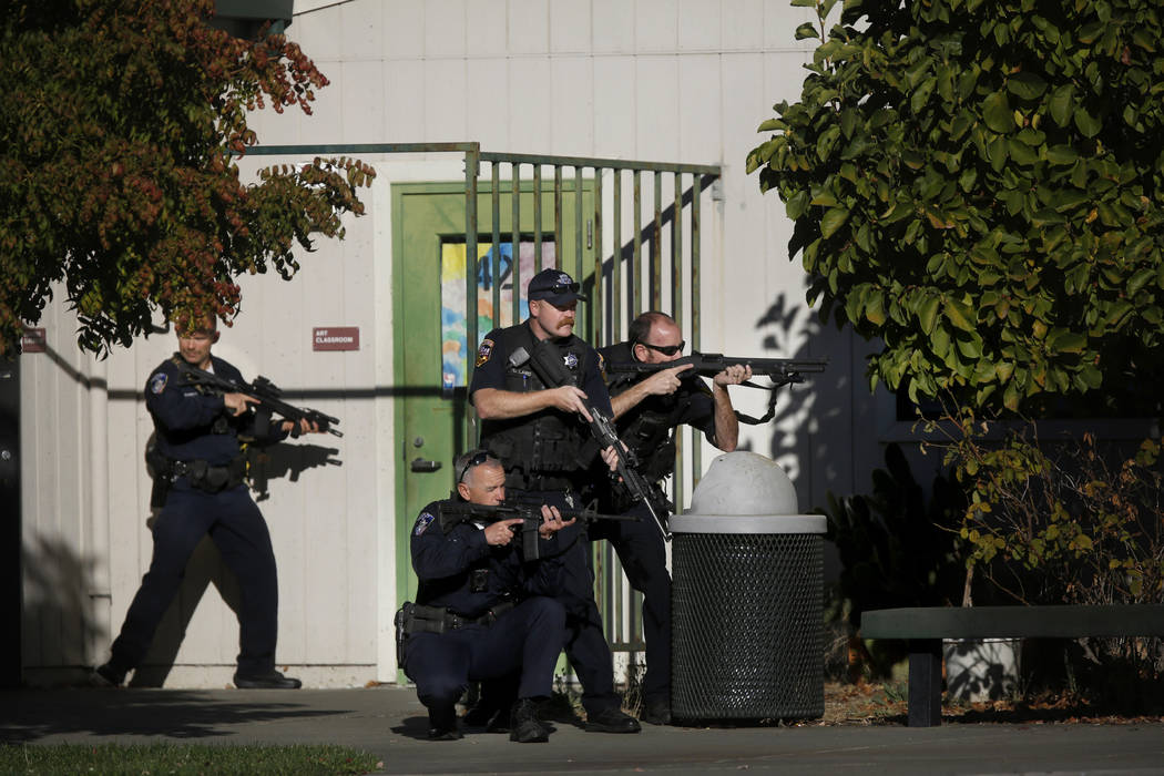 Santa Rosa police officers hold guns as they search the campus of Ridgway High School for suspe ...