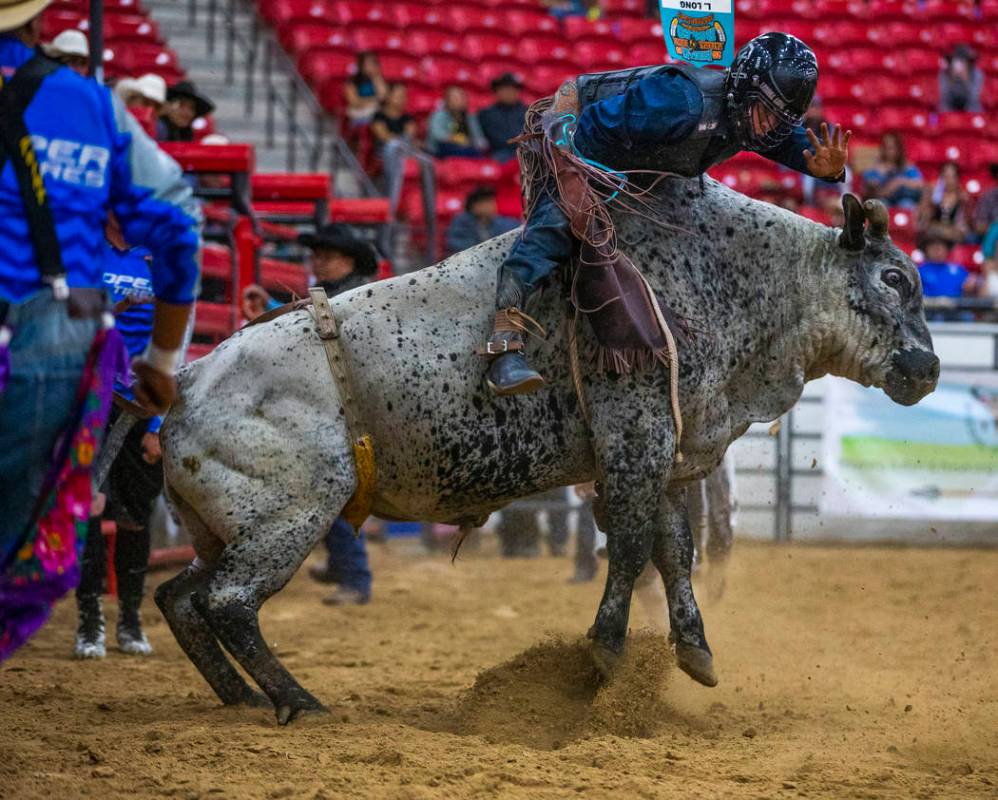 Bull rider Latrell Long is pushed forward but continues to hang onto his bull during the first ...