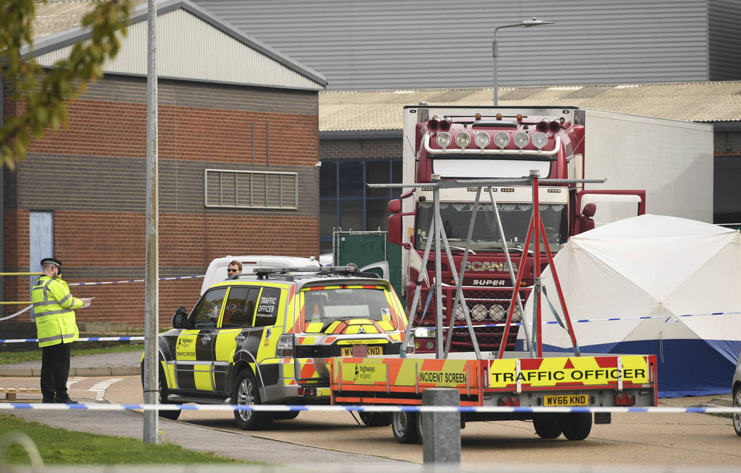 Police officers attend the scene after a truck, seen in rear, was found to contain a large numb ...