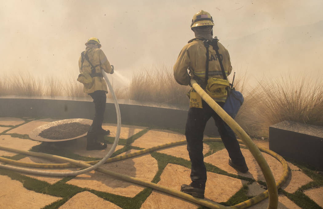 Firefighters protect a home from a wildfire in the Pacific Palisades area of Los Angeles, Monda ...
