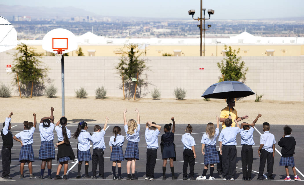 Physical education teacher Jason Ellis checks in with his class to see if they abided by R.A.I. ...