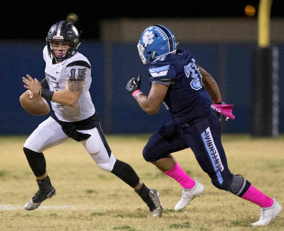 Palo Verde senior quarterback Paul Myro (15) scrambles away from Centennial senior Leonard Robb ...