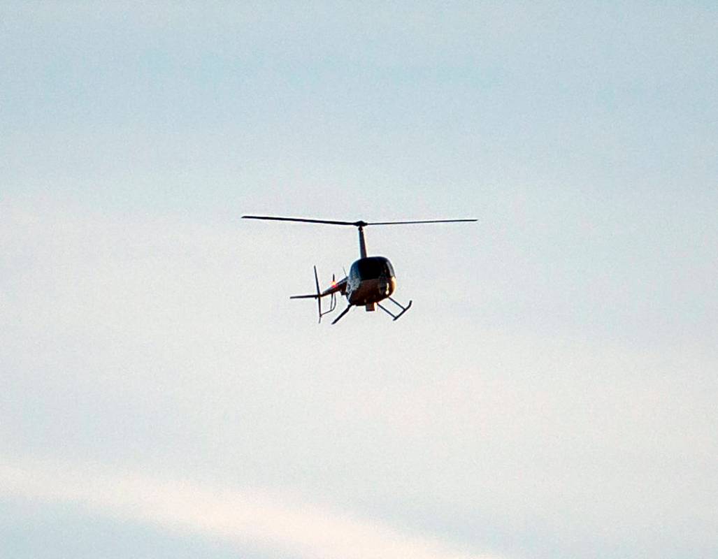 A helicopter flies above state Route 159 in response to a helicopter crash in the Red Rock Cons ...