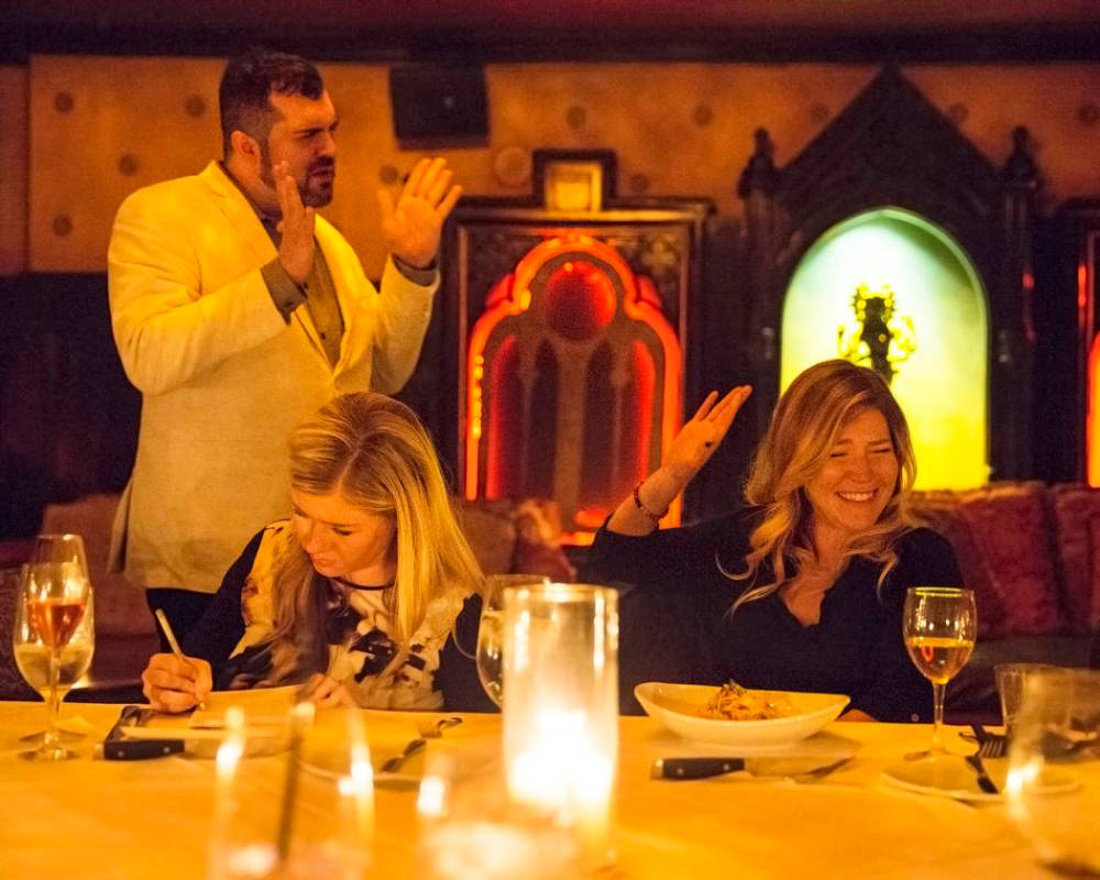 Psychic medium Thomas John, left, provides readings to guests during Dinner with the Dead on Fr ...