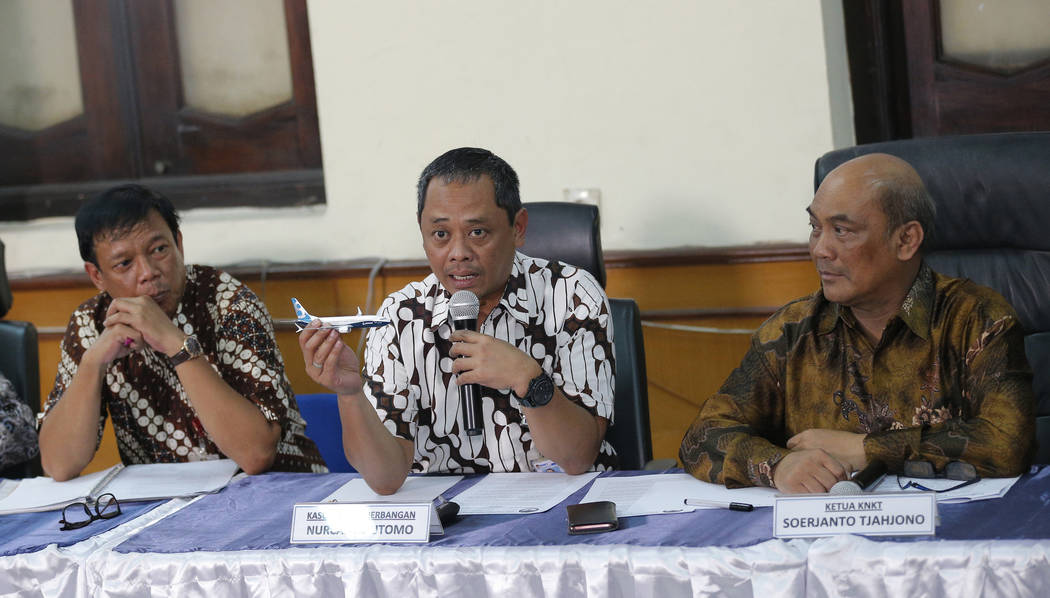 National Transportation Safety Committee investigator Nurcahyo Utomo, center, holds a model of ...