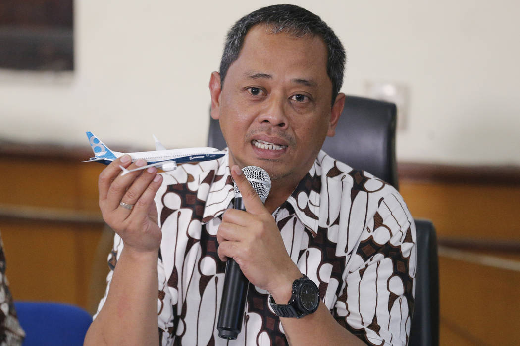 National Transportation Safety Committee investigator Nurcahyo Utomo holds a model of an airpla ...