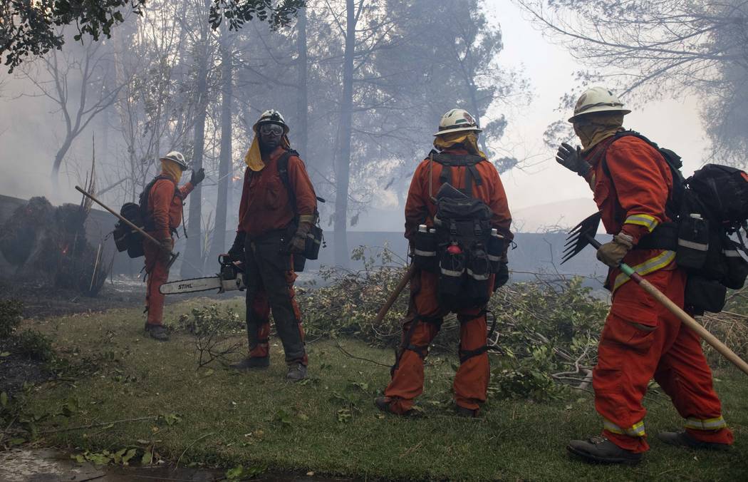 Firefighters from Holton Fire Camp 16 work to contain the Tick Fire behind a residential home i ...