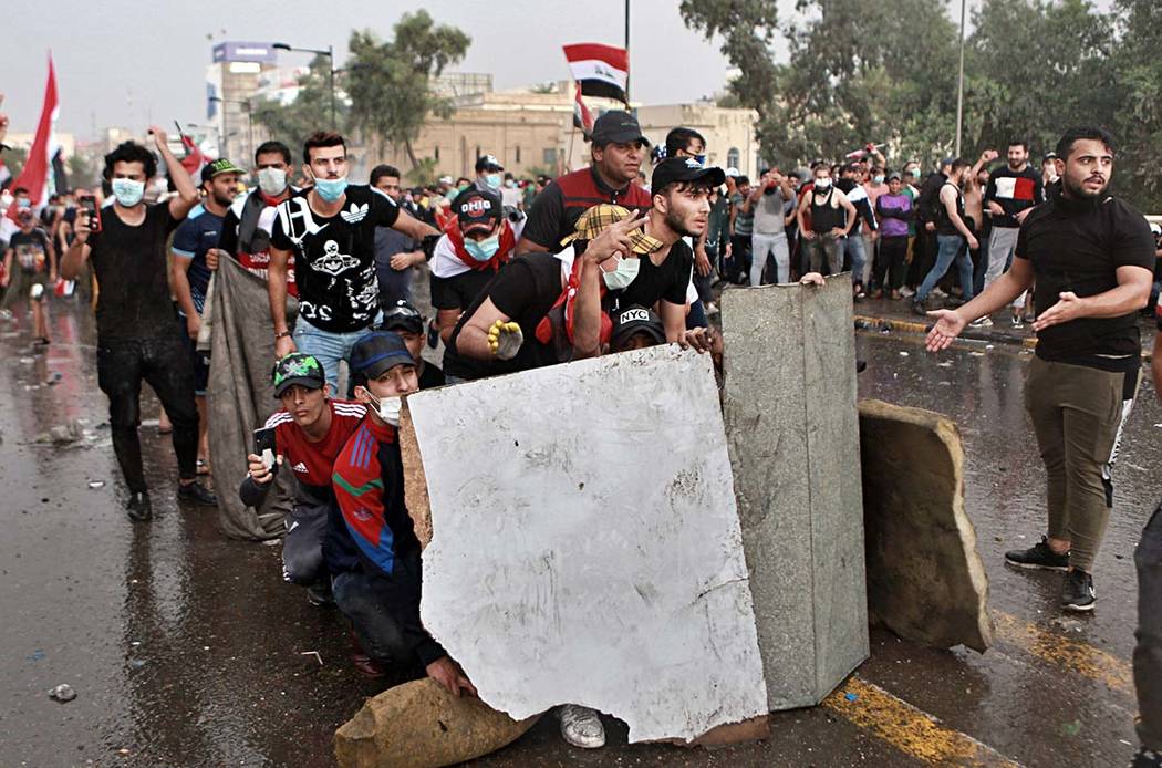 Anti-government protesters take cover while Iraq security forces fire during a demonstration in ...