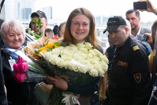 Russian agent Maria Butina, center, holds a bunch of flowers upon her arrival from the United S ...