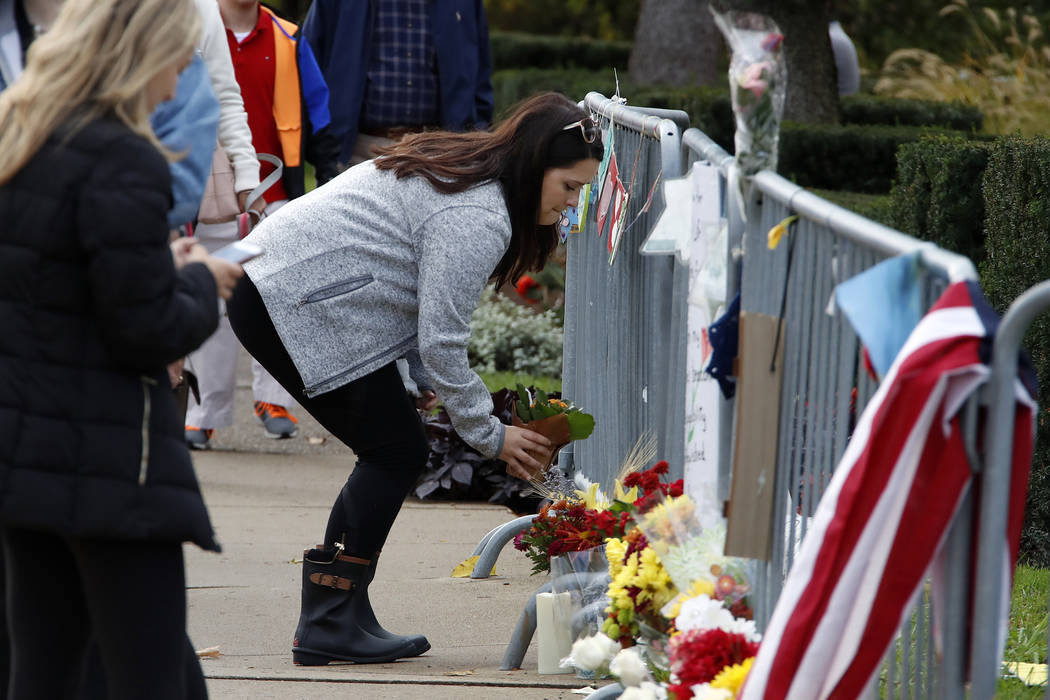 A woman places a flower along a fence outside the Tree of Life synagogue in Pittsburgh on Sunda ...