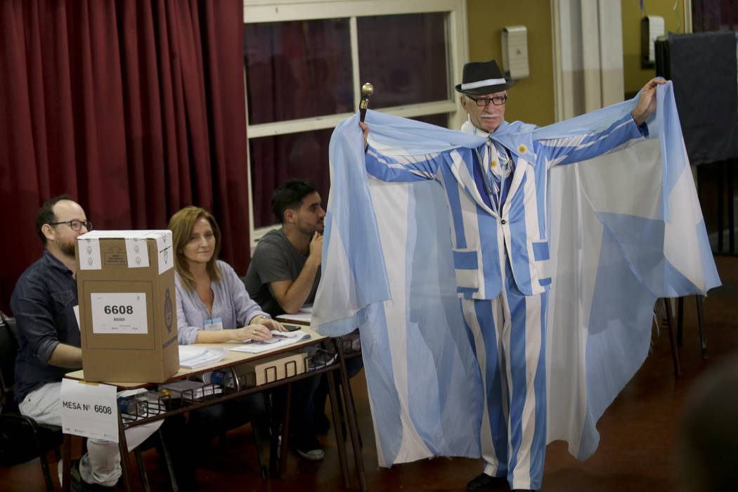 A man shows off his Argentine flag motif suit and cape before voting in Buenos Aires, Argentina ...