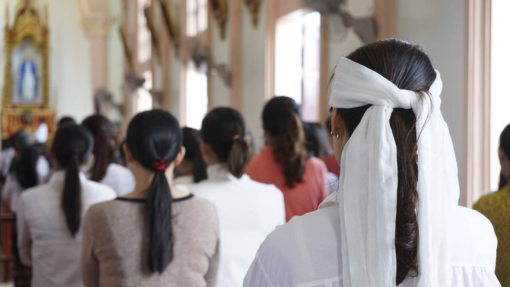 A woman wearing a white head band, traditionally worn by relatives of a deceased person during ...