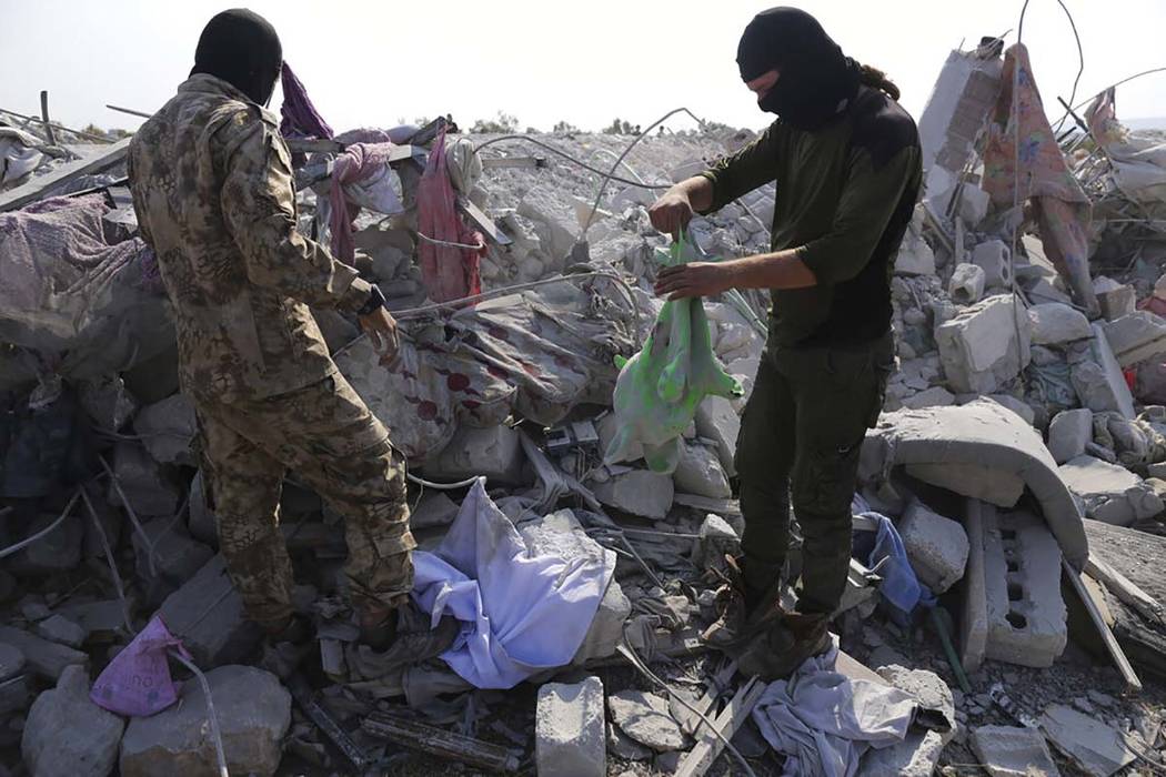 People look at a destroyed houses near the village of Barisha, in Idlib province, Syria, Sunday ...