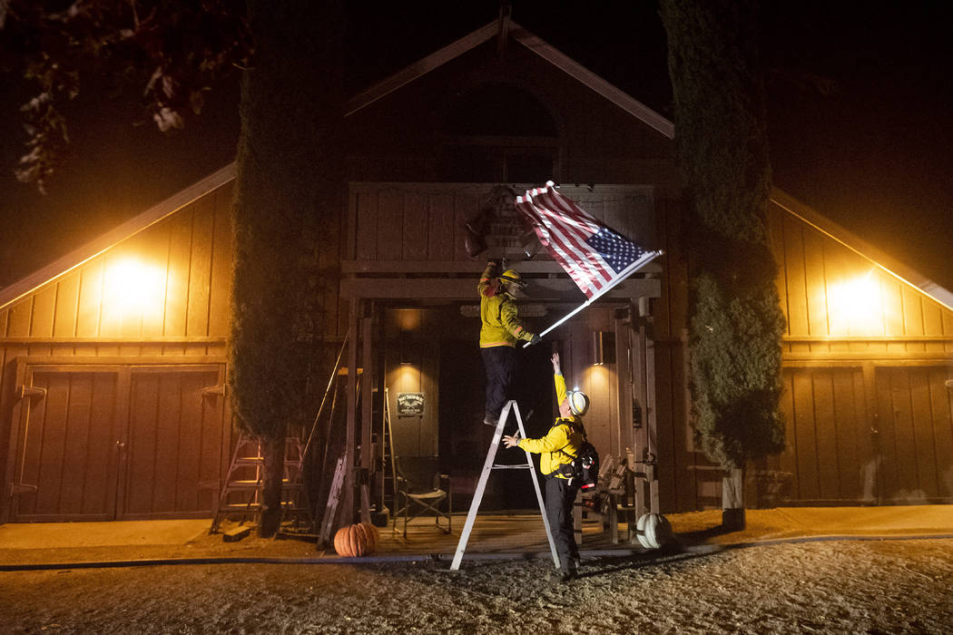 Firefighters from Dry Creek Rancheria remove an American flag as the Kincade Fire bears down on ...