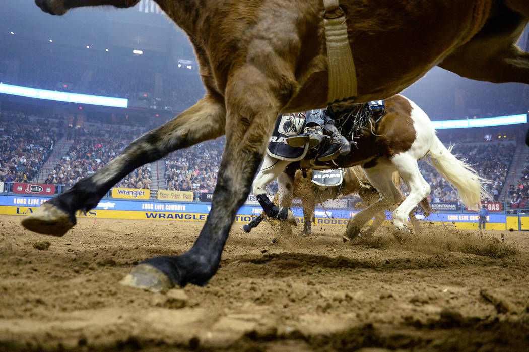 A line of horses run through the arena during the sixth go-round of the National Finals Rodeo a ...