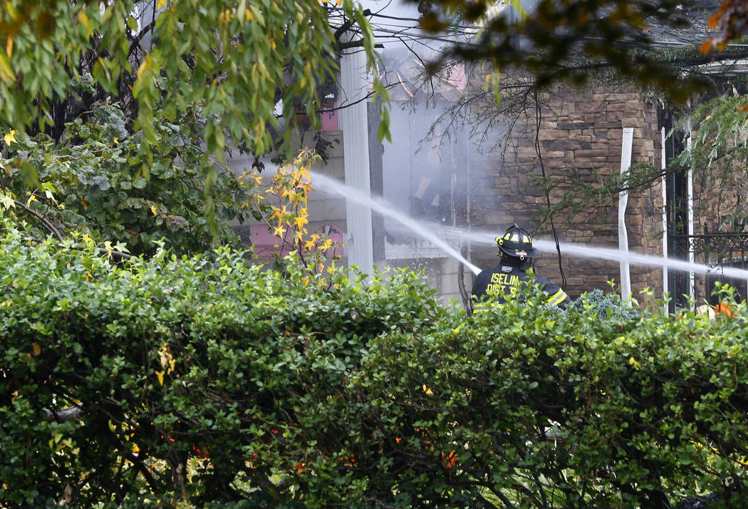 Woodbridge firefighters work to extinguish the scene of a plane crash at a home Tuesday, Oct. 2 ...