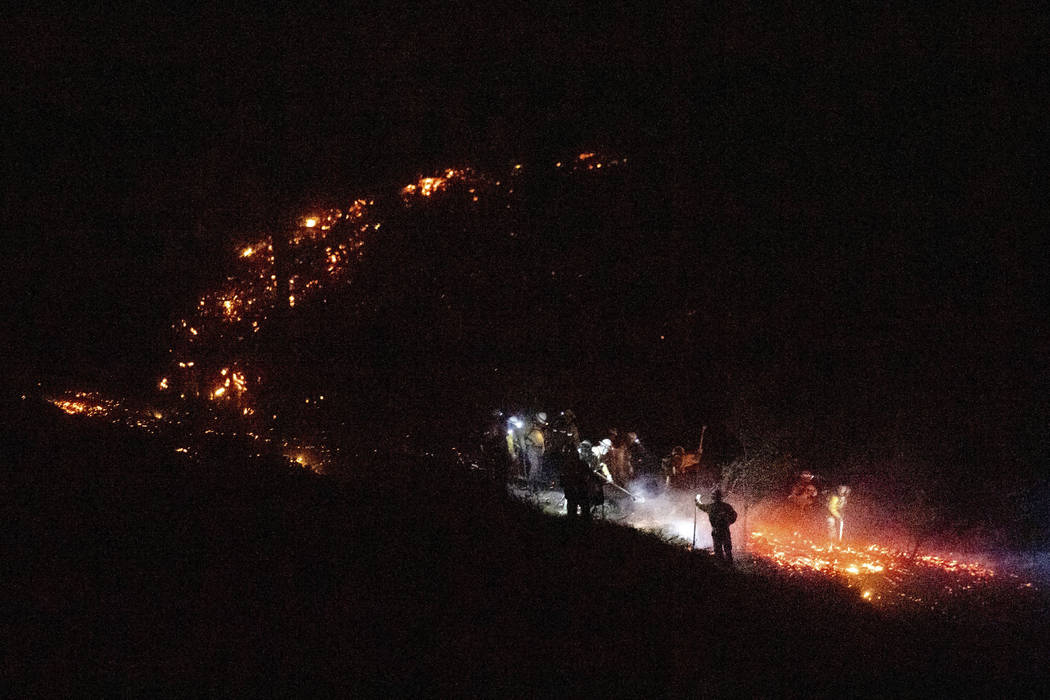 Firefighters work to douse a flare-up as the Kincade Fire burns through a vineyard in Calistoga ...