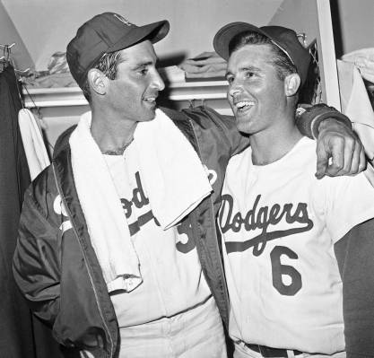 Dodger left hander Sandy Koufax, left, gets congratulations from outfielder Ron Fairly after wi ...